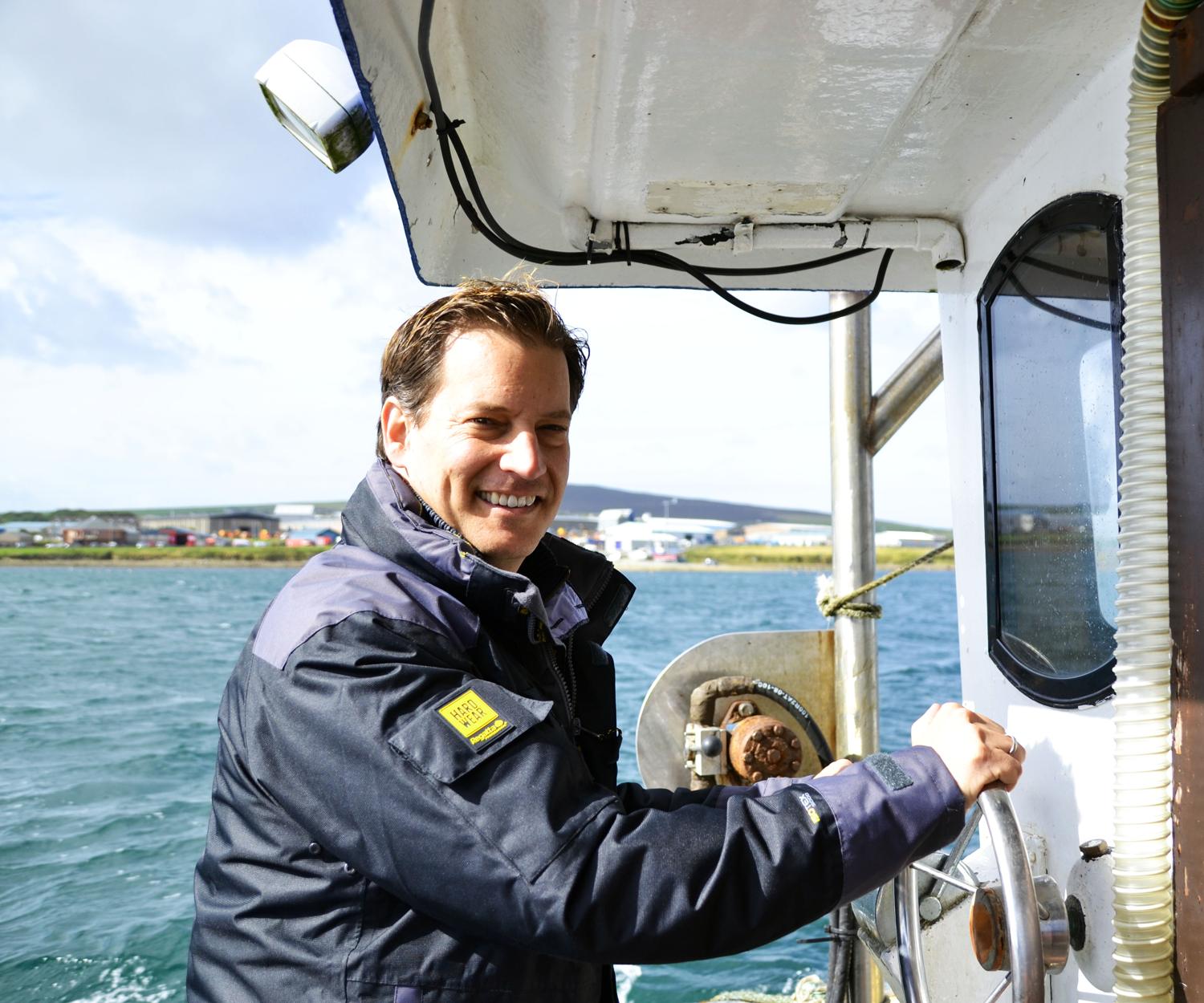 André Fröhlich lächelnd am Steuer eines Bootes auf dem Wasser